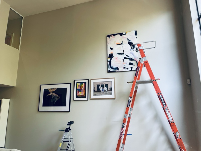 Gallery wall installation in progress with ladder