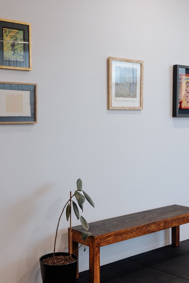 Framed artworks on gallery wall with bench